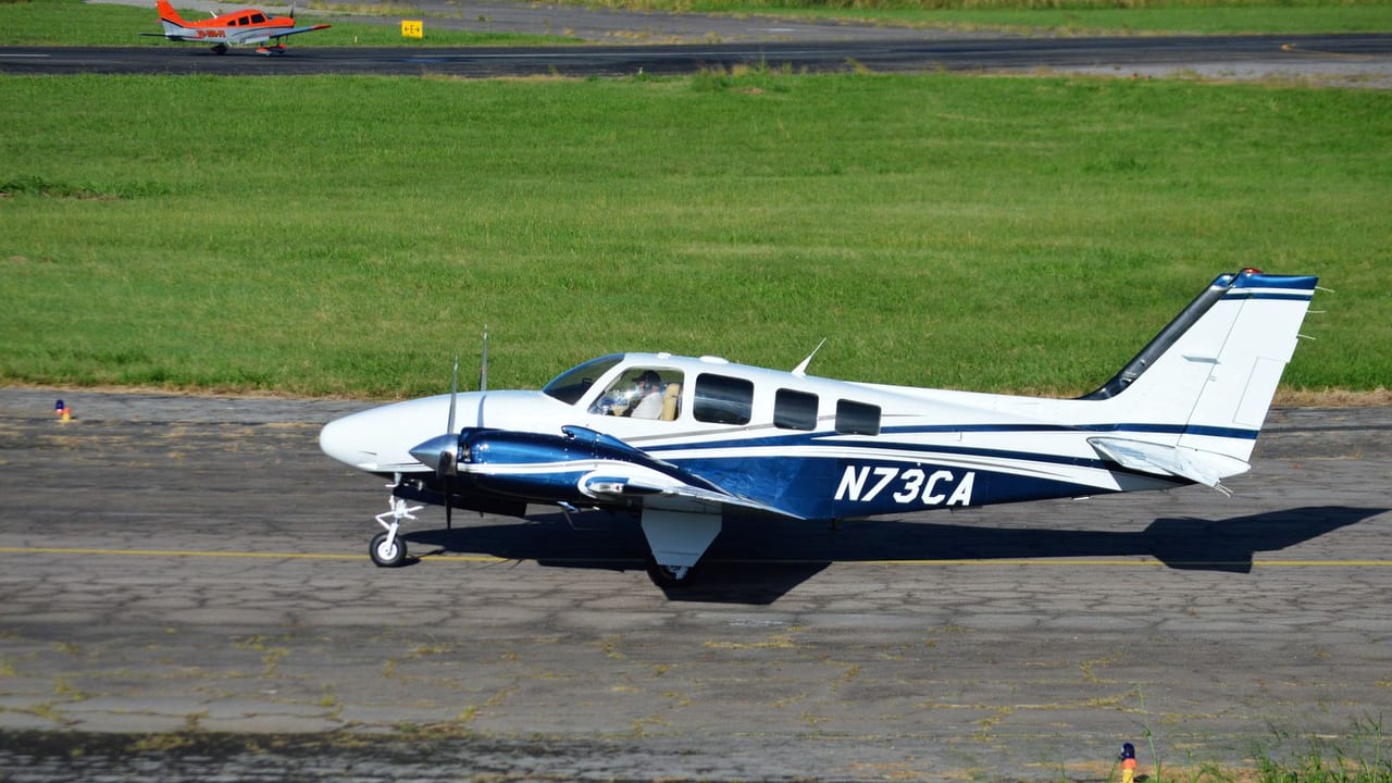 A single-engine aeroplane taxiing along a runway edge on a sunny day