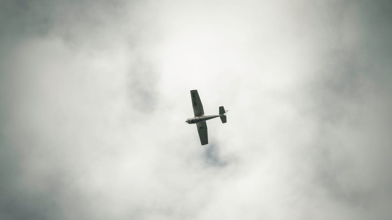 A light aeroplane flying beneath a thick, building cloud layer