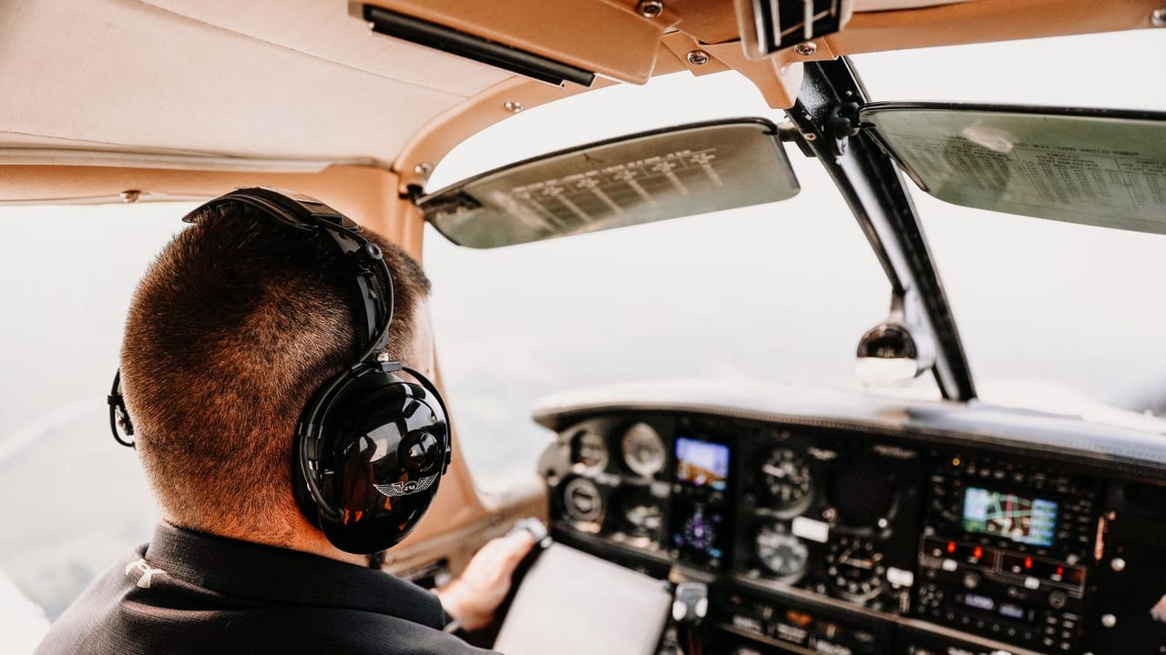 A pilot in a headset concentrating on the instruments in flight